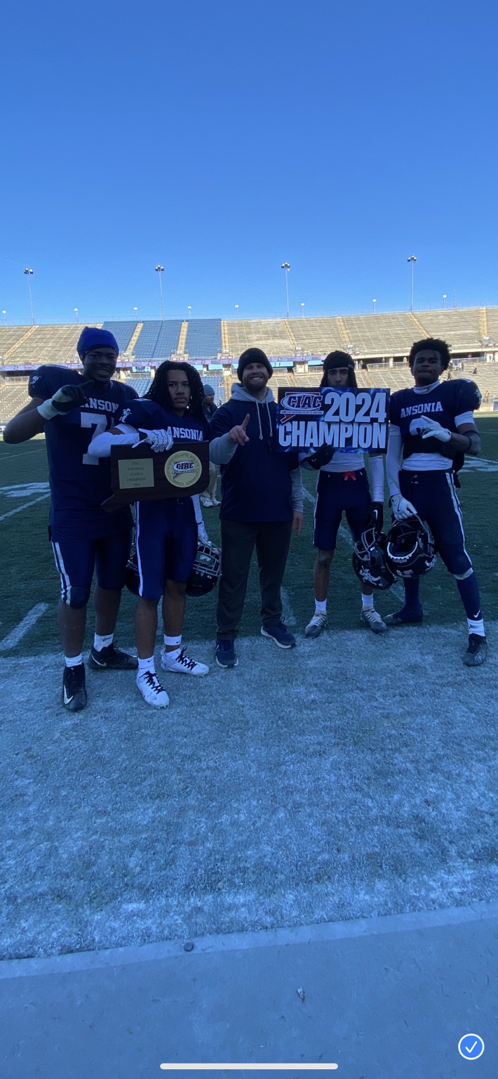 Coach with athletes holding 2024 championship sign